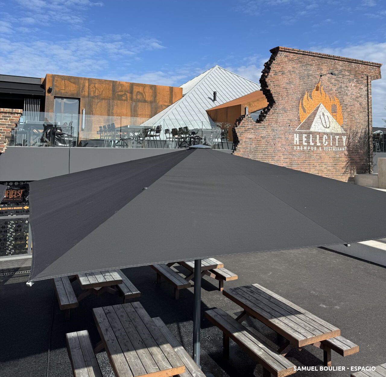 Comptoir extérieur du Hellcity sous auvent, ambiance bois et jeux d’ombre